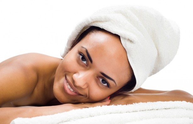 Mulher deitada com toalha na cabeça | Cuidados com a pele negra feminina