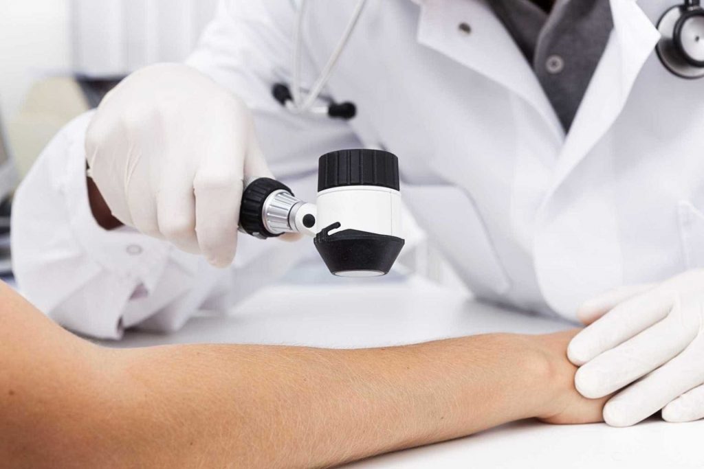 Paciente com o braço esticado sendo analisado pelo médico | O que é furúnculo?